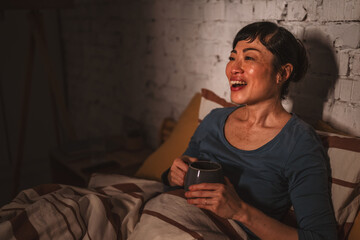 Fototapeta premium Woman enjoying morning coffee laughing in bed