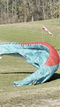 paraglider folding his parachute on landing meadow