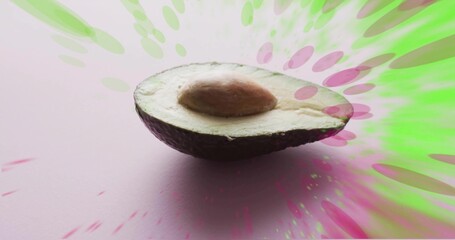 Resting halved avocado showing pale green flesh and brown pit on pastel pink, neon bursts © vectorfusionart