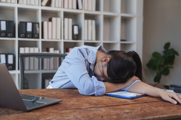 Fototapeta premium Exhausted businesswoman sleeping on desk during work
