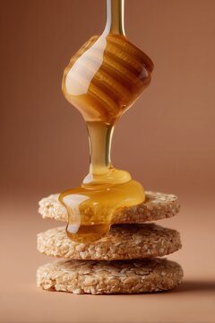 Golden honey dripping from a wooden dipper onto a stack of oatcakes