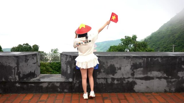 Asia Vietnam 03,06,2026  - vietnamise lady girl with flag and hat - The fortress on the Hai Van Pass is anancient defensive gate  on the border between Da Nang and Hue ,  American military bunkers