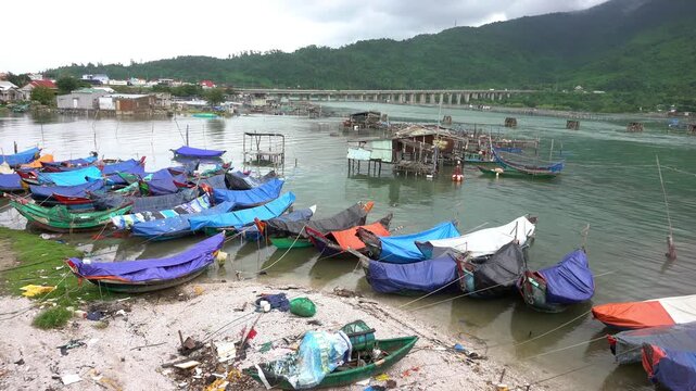 Stilt houses and fishing boats in a small natural harbor in Vietnam near Hoi An, traditional life in poverty in Asia Vietnam