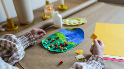 Fototapeta premium Child's hands crafting a colorful paper collage with glue and small paper pieces