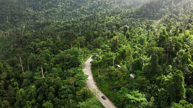 Drone shot of black car driving along winding tropical mountain road Philippines