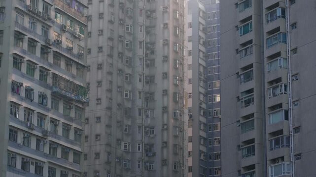 Panoramic view of apartment buildings and skyscrapers in downtown Hong Kong, China on a sunny day, showcasing dense urban living and modern architecture.