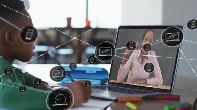 Boy writing workbook while laptop tutor sending icon net spreading over hands for education