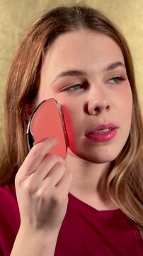 A young woman enjoys a facial massage with a microcurrent massager. Professional body treatment. Wrinkle smoothing.