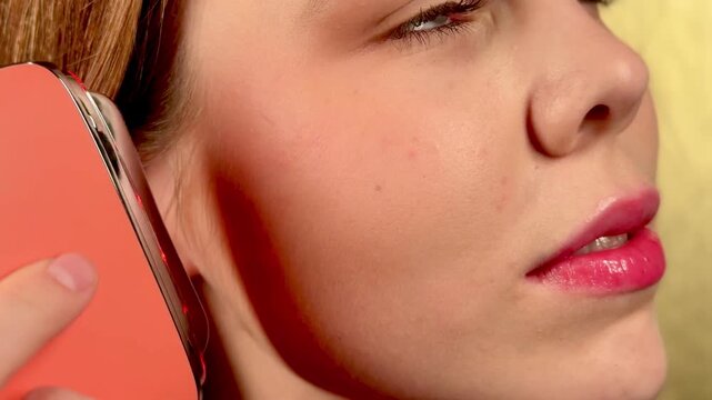 A young woman enjoys a facial massage with a microcurrent massager. Professional body treatment. Wrinkle smoothing.