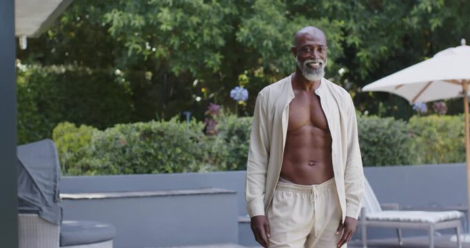 Senior African American man shifting stepping to lens and smiling wearing open shirt on patio