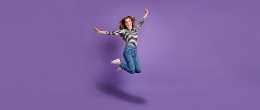 Dynamic jumping action by a young woman studio setting lifestyle content vibrant purple background full-body perspective celebrating joy and freedom