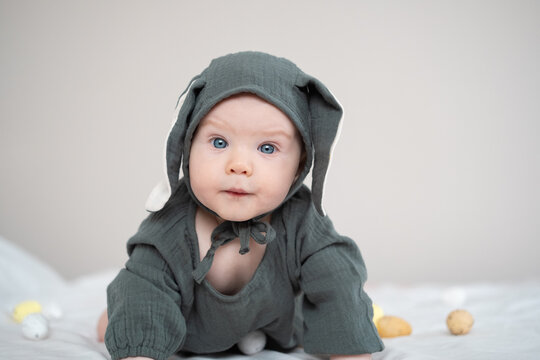 A cute boy in a bunny costume plays with colorful Easter eggs on a spring day. Funny child on Easter.