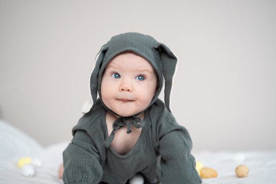 A cute boy in a bunny costume plays with colorful Easter eggs on a spring day. Funny child on Easter.