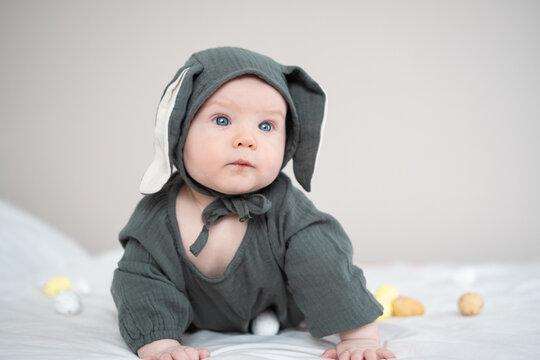 A cute boy in a bunny costume plays with colorful Easter eggs on a spring day. Funny child on Easter.