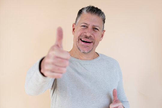 Man with gray hair and brown sweater standing in front of brown background