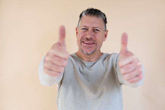 Man with gray hair and brown sweater standing in front of brown background
