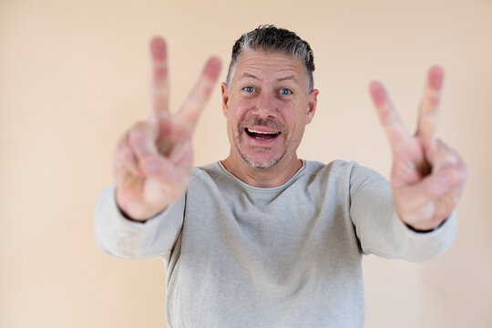 Man with gray hair and brown sweater standing in front of brown background