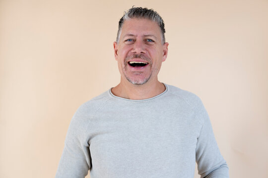 Man with gray hair and brown sweater standing in front of brown background