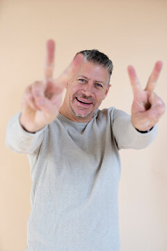 Man with gray hair and brown sweater standing in front of brown background