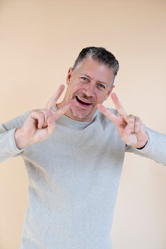 Man with gray hair and brown sweater standing in front of brown background