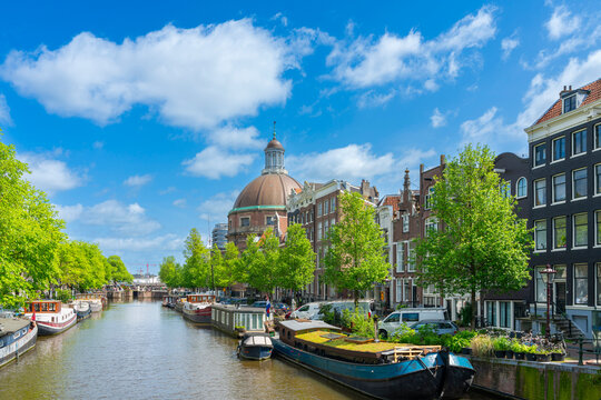 Ronde Lutherse Kerk with boats moored in Singel canal against sky, Amsterdam, Netherlands