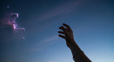 Fototapeta premium A dark hand reaches for a colorful nebula in a starry night sky, representing aspiration, longing, and a connection to the vastness of the universe