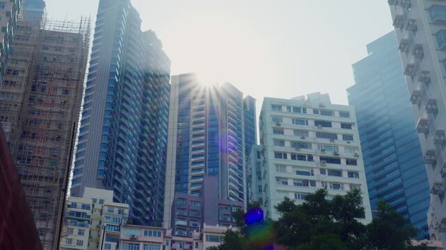 Panoramic view of apartment buildings and skyscrapers in downtown Hong Kong, China on a sunny day, showcasing dense urban living and modern architecture.