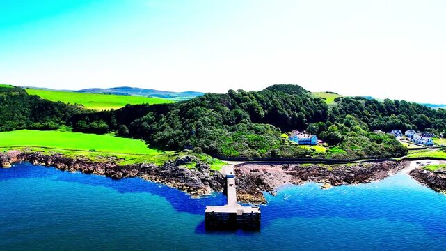 Portencross near Largs, North Ayrshire, Scotland, UK, revealing a small pier, rocky shoreline, green field and calm blue sea under clear summer light, cinematic aerial view