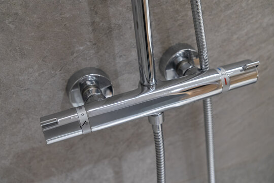 Modern chrome thermostatic shower mixer tap mounted on a grey tiled wall, featuring temperature controls and 40 marking for precise water regulation in a contemporary bathroom
