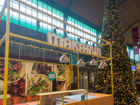 Wroclaw, Poland - December 15, 2025: MAKARUN pasta eatery with appetizing food, bright lights, by towering illuminated Christmas tree