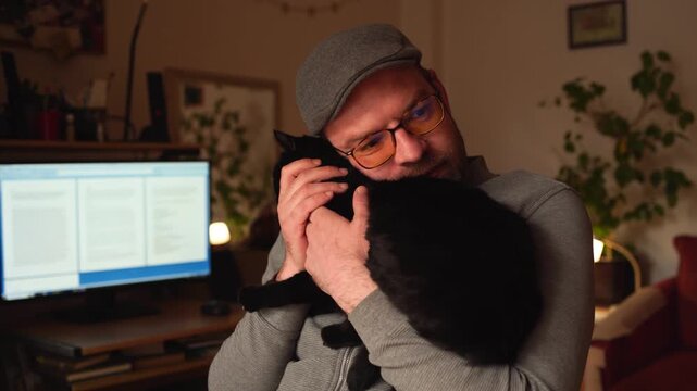 Man playing with a black pet cat in the home office