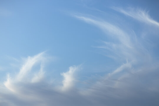 Dynamic cirrus cloud formation on blue sky with flowing natural pattern. Blue sky with dynamic cirrus clouds forming flowing, wave-like shapes. The movement in the clouds adds energy while maintaining