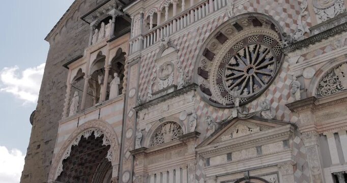 Renaissance marble front of Cappella Colleoni in Bergamo Alta, smooth pan reveals the large rosette window with radiating spokes above ornate arches as pastel stone inlays and sculpted figures
