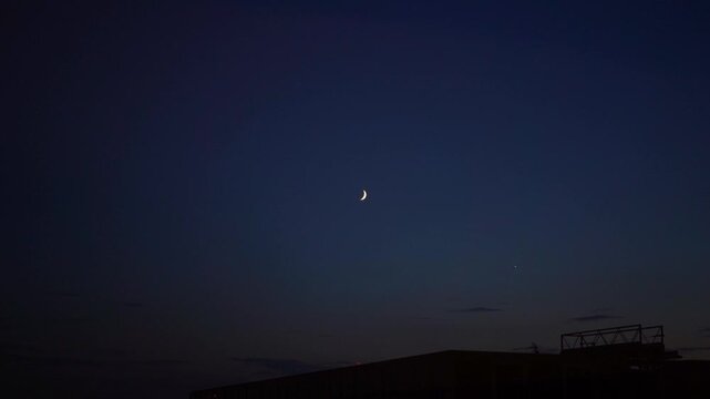 Moonrise over the city skyline at dusk with clear sky and soft light