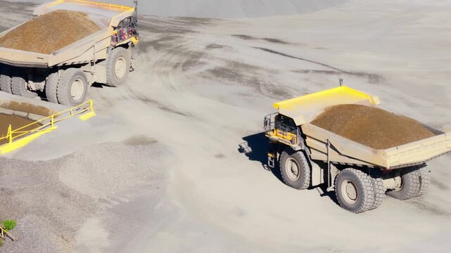 Aerial tilt up of two haul trucks carrying aggregate at American quarry
