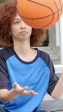 Vertical video: Starting clip woman in sports top spinning basketball on steps, practicing control