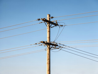 Solitary Wooden Utility Pole with Electrical Wires Against a Clear Blue Sky, Symbolizing Connection and Infrastructure.