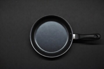 A black frying pan rests on a dark surface.