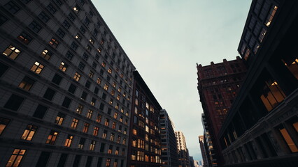 Naklejka premium golden hour avenue with glowing windows, busy commercial corridor flanked by ornate brick and glass towers, warm interior lights create cozy amber glow,