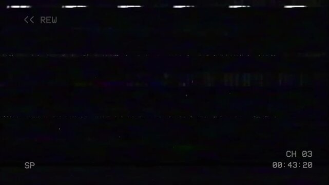Vintage VHS rewind screen with analog noise and glitch artifacts. Static lines flicker across a dark frame while the tape rewinds, showing classic &ldquo;REW&rdquo;, SP mode, and channel display.