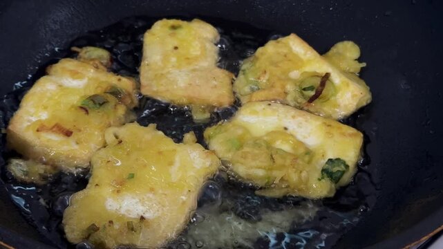 Indonesian traditional food Tahu Goreng or Fried Tofu.Cubes Deep Frying in Hot Oil with Bubbling Texture Close Up