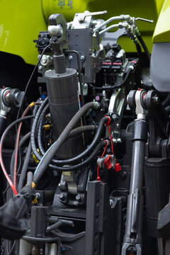 Close up of complex hydraulic system on a tractor hitch with cylinders, pistons and hoses. Powerful agricultural machinery detail for precise farm implement control and field work