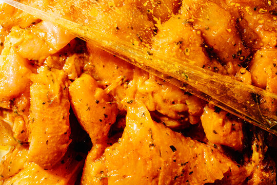 raw chicken marinating with spices in a plastic bag