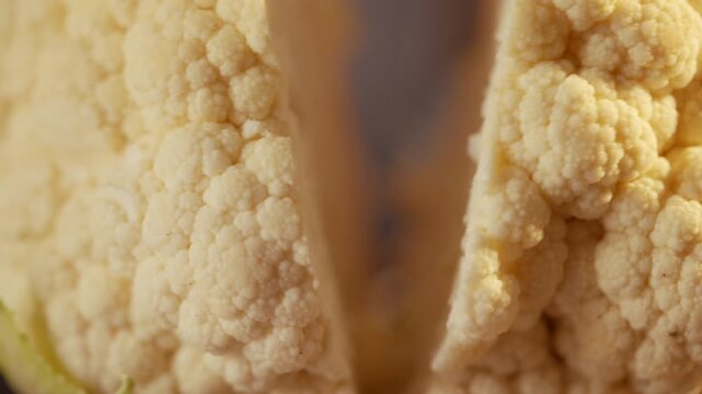 Cauliflower close-up split vertically, creamy white florets detailed. Smooth texture, natural lighting highlights fresh produce. Ideal for food blogs, recipes, or healthy eating content