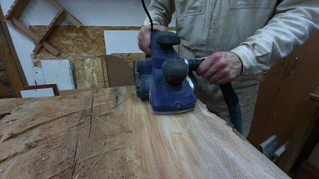 Authentic Unrecognizable Artisan Revealing Natural Wood Grain with Electric Planer Close Up Tracking Shot