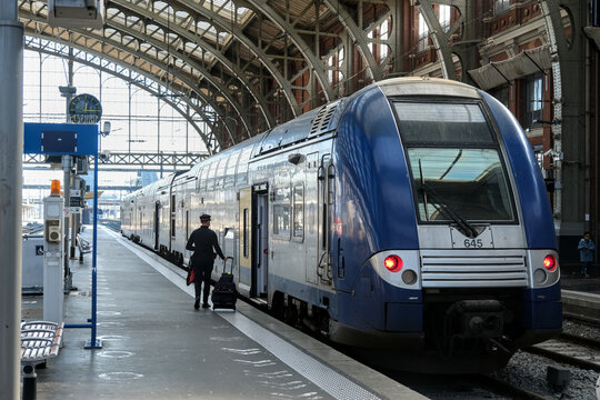 SNCF train driver walks along platform to take duty on a regional train inside a historic railway station in France.