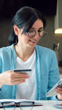 Bussines woman enters bank credit card digits smartphone to make online purchase. Brunette famele online banking with credit card and phone in a home online shopping at home. Slow motion.