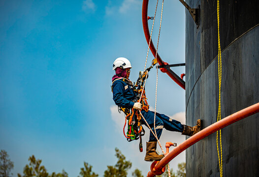 Male worker rope down access safety inspection of pipe fire water repair storage tank