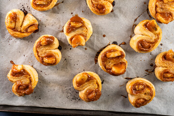 Freshly baked banana caramel puff pastry rolls on a baking sheet. Pastry. Dessert © Denis
