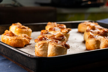 Freshly baked banana caramel puff pastry rolls on a baking sheet. Pastry. Dessert © Denis
